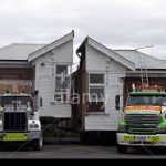 House cut in half on moving truck beds
